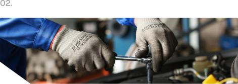 Blue-gloved hand pouring dark liquid from a black spout into a container in an industrial setting
