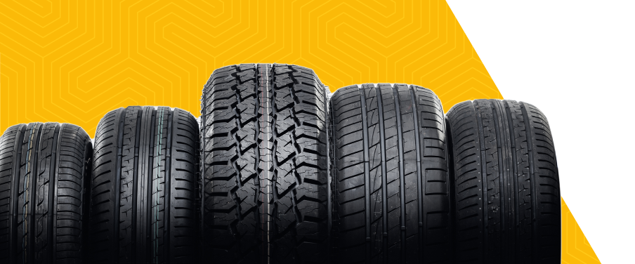 Row of black car tires on a black surface against a yellow background