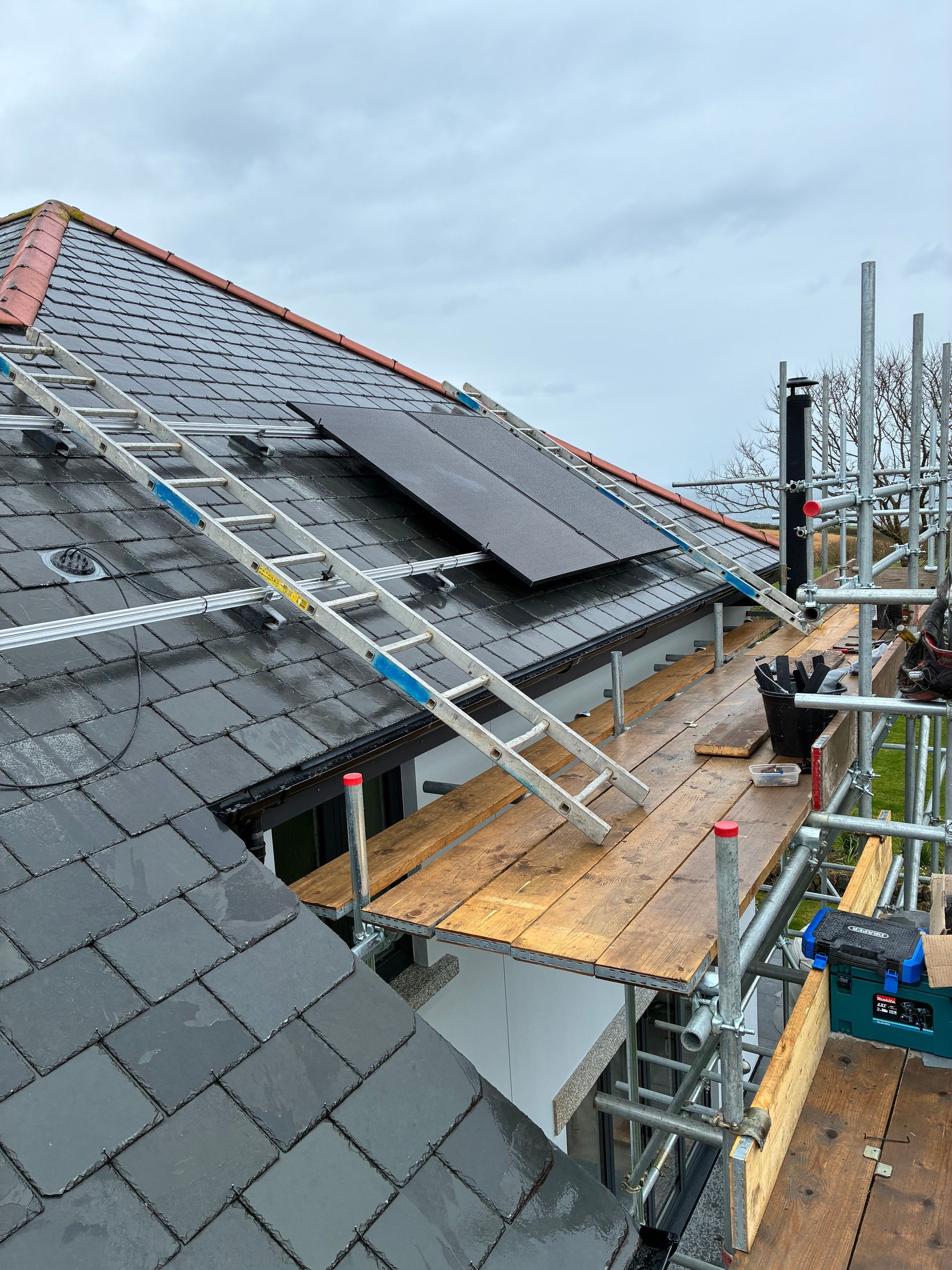Three roofers installing shingles on a house roof on a sunny day.