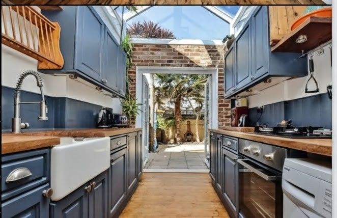 Modern kitchen with gray cabinets, wooden island with stools, and stainless steel appliances.