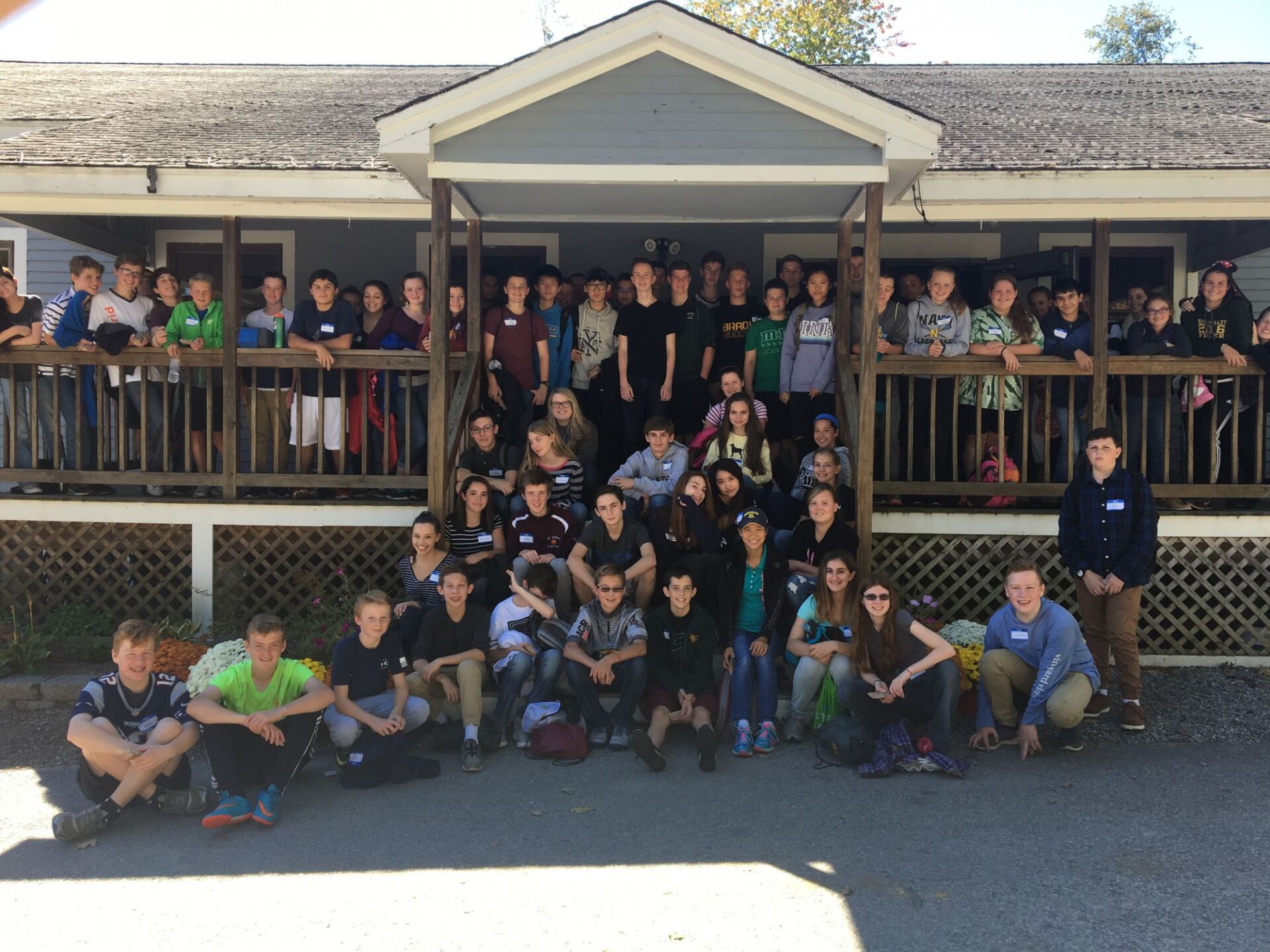 group of students sitting on deck and front steps of a house