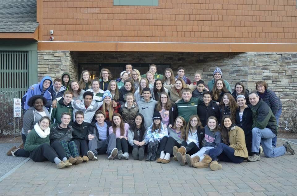 group of students outside in front of a gray and brown building 