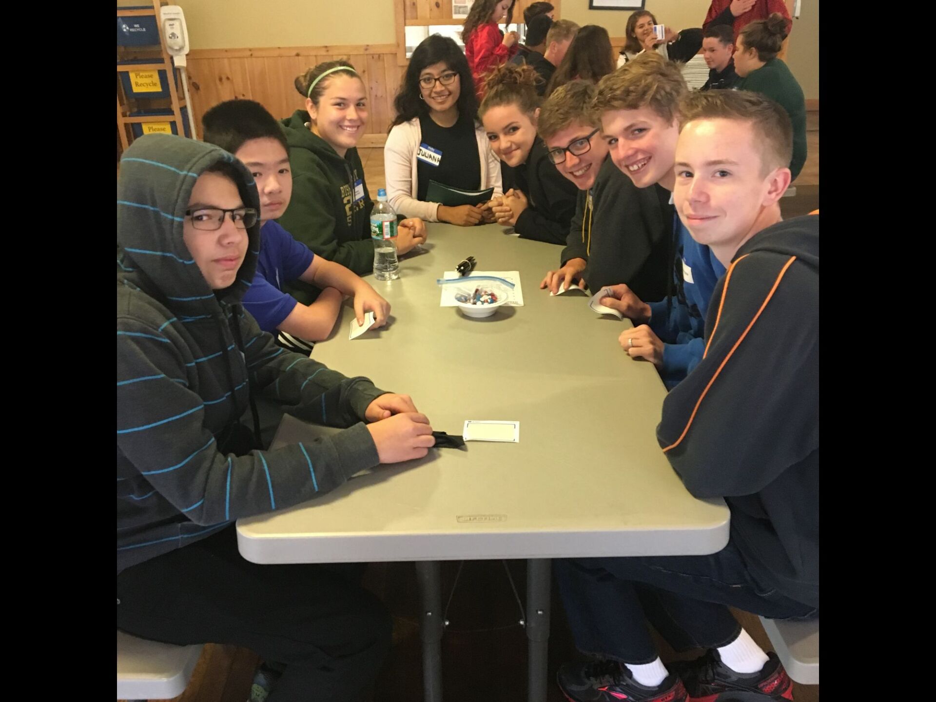 group of students smiling while siting at a long table 