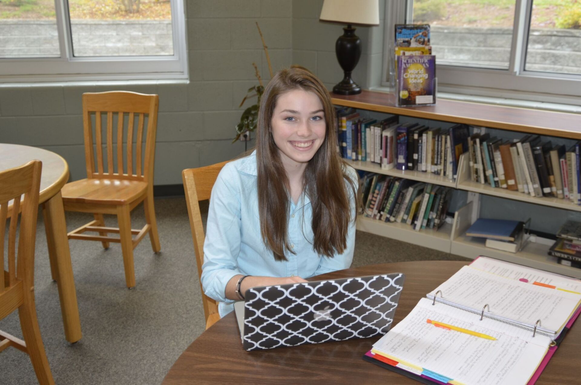 female student on a laptop smiling while siting in the library