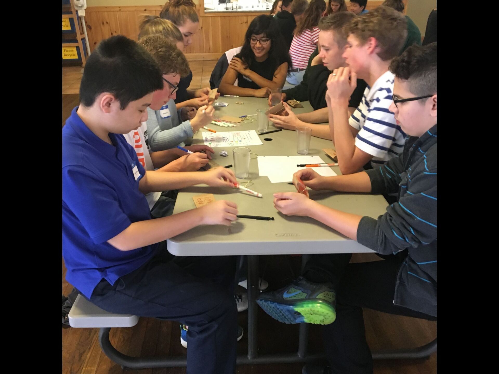 group of students sitting at table with pens and paper