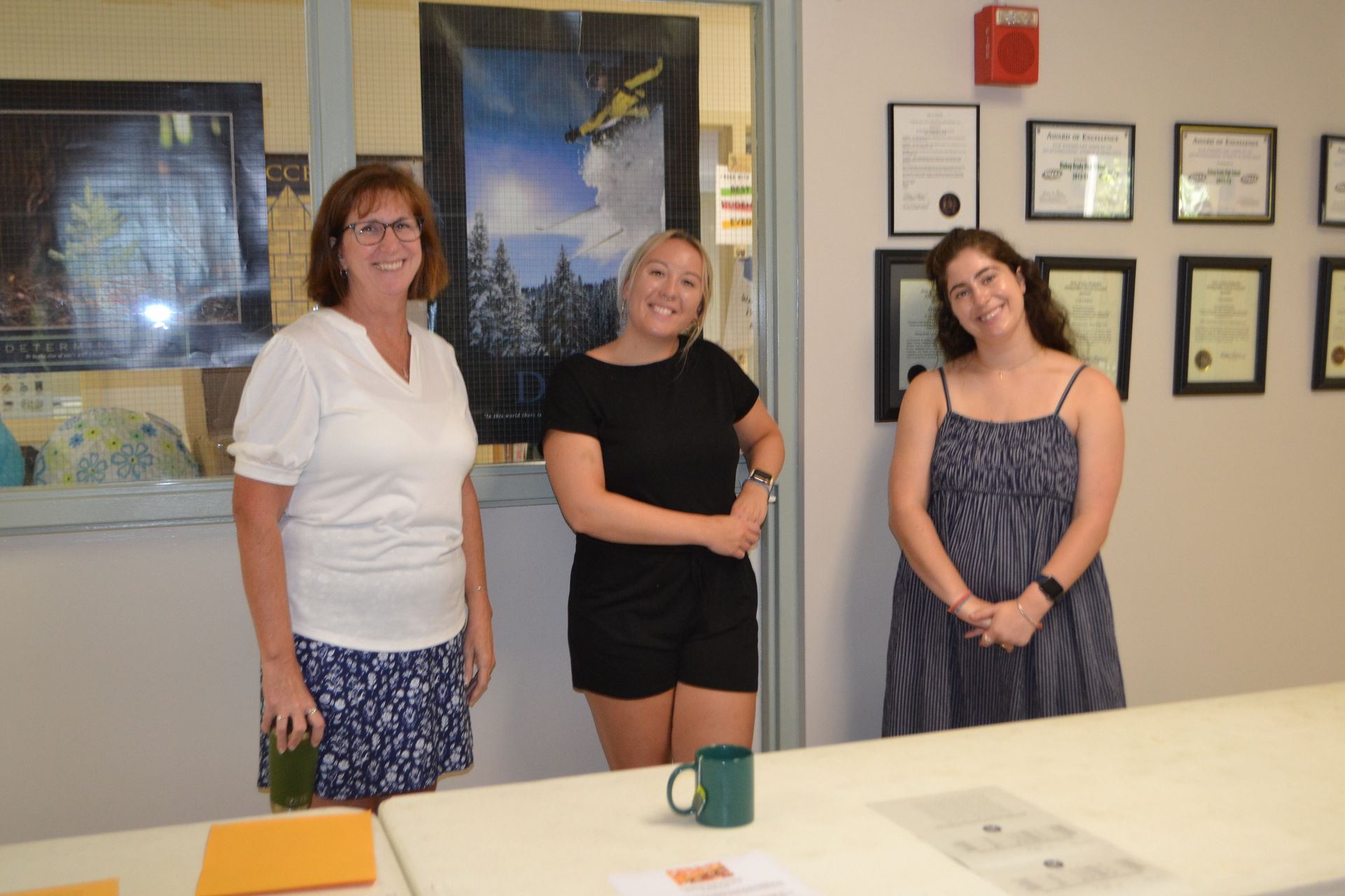 3 people smiling in a doorway classroom 
