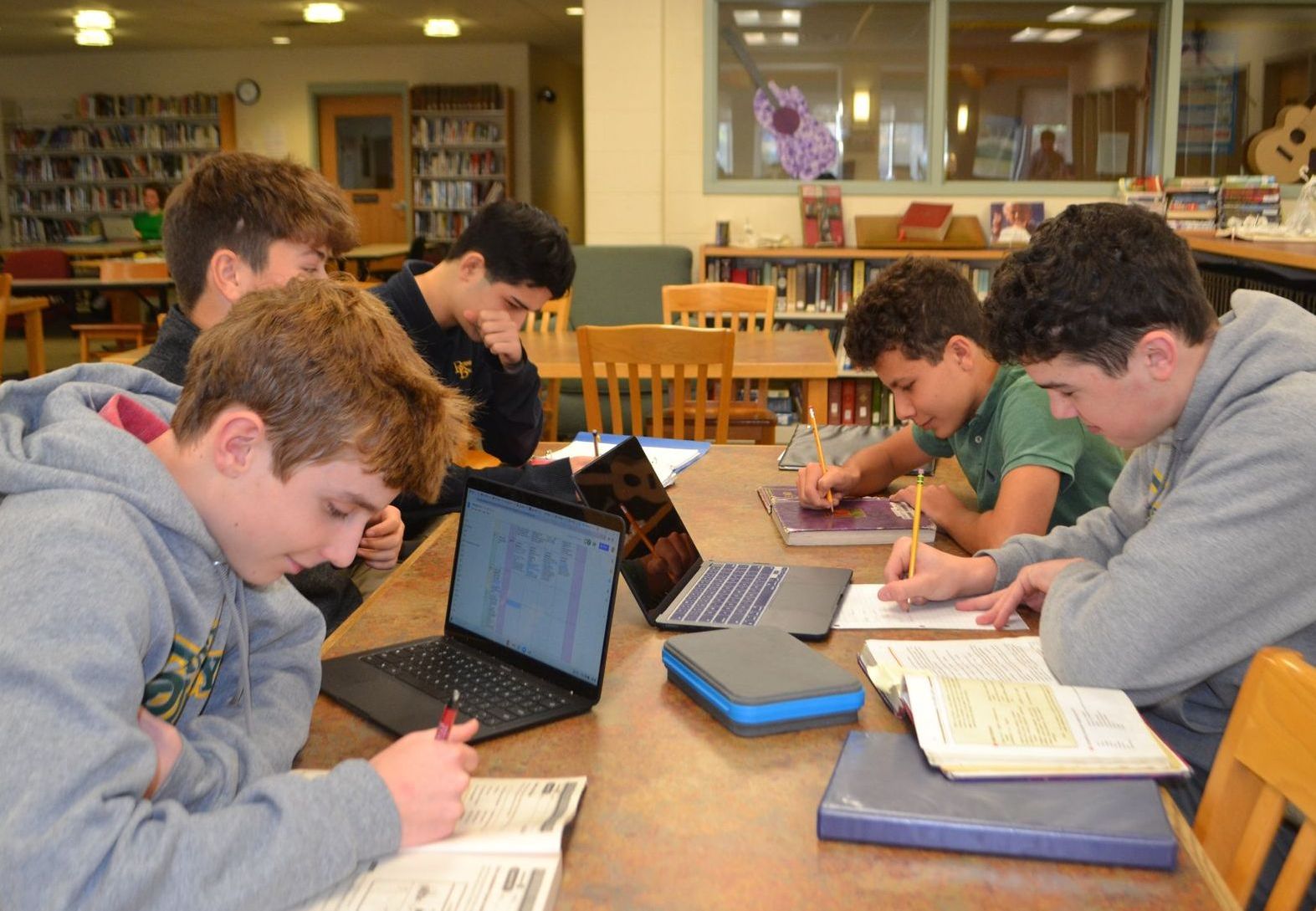 image of students studying with desk, laptops and books 