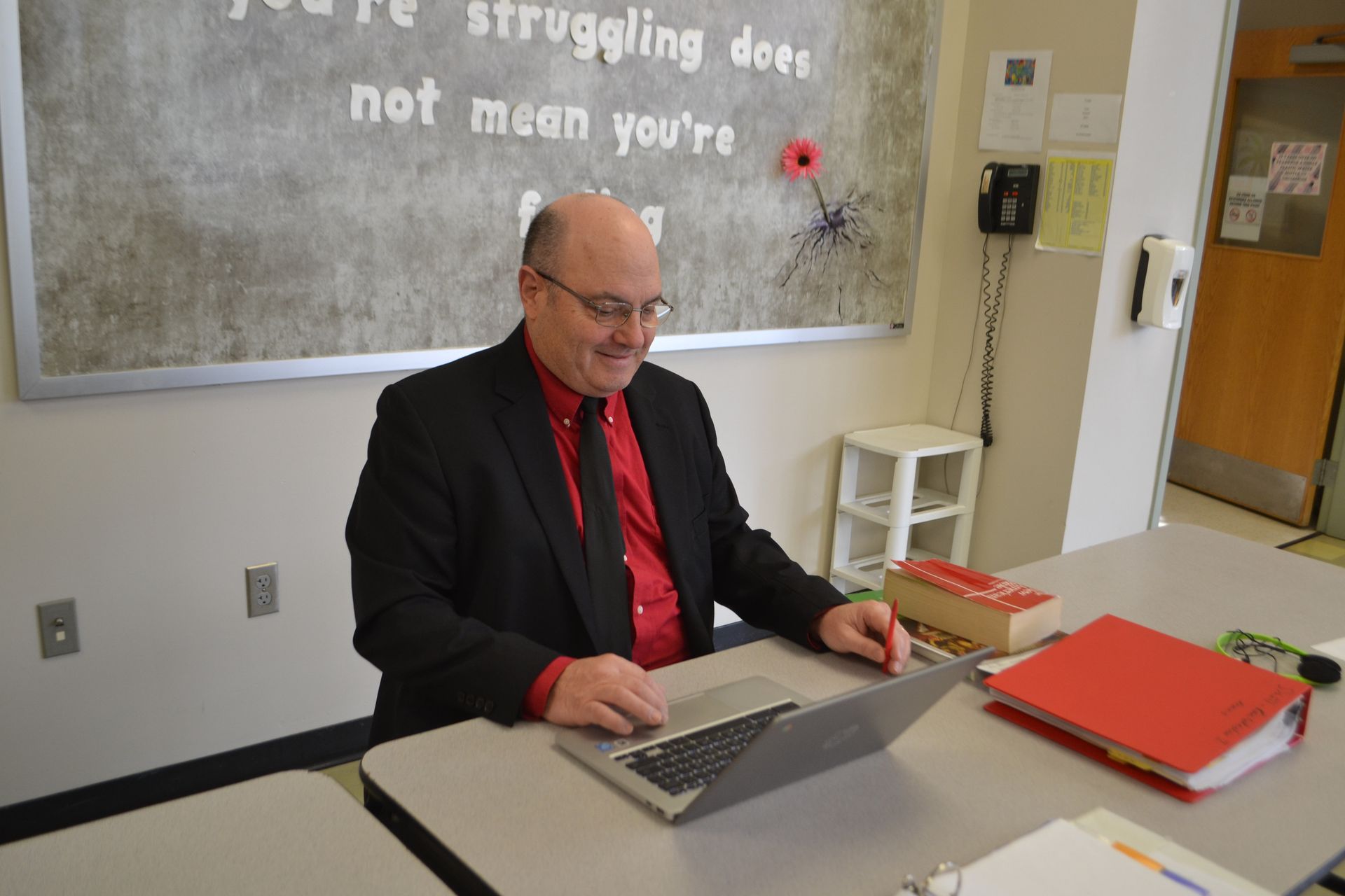 teacher sitting at table with computer 