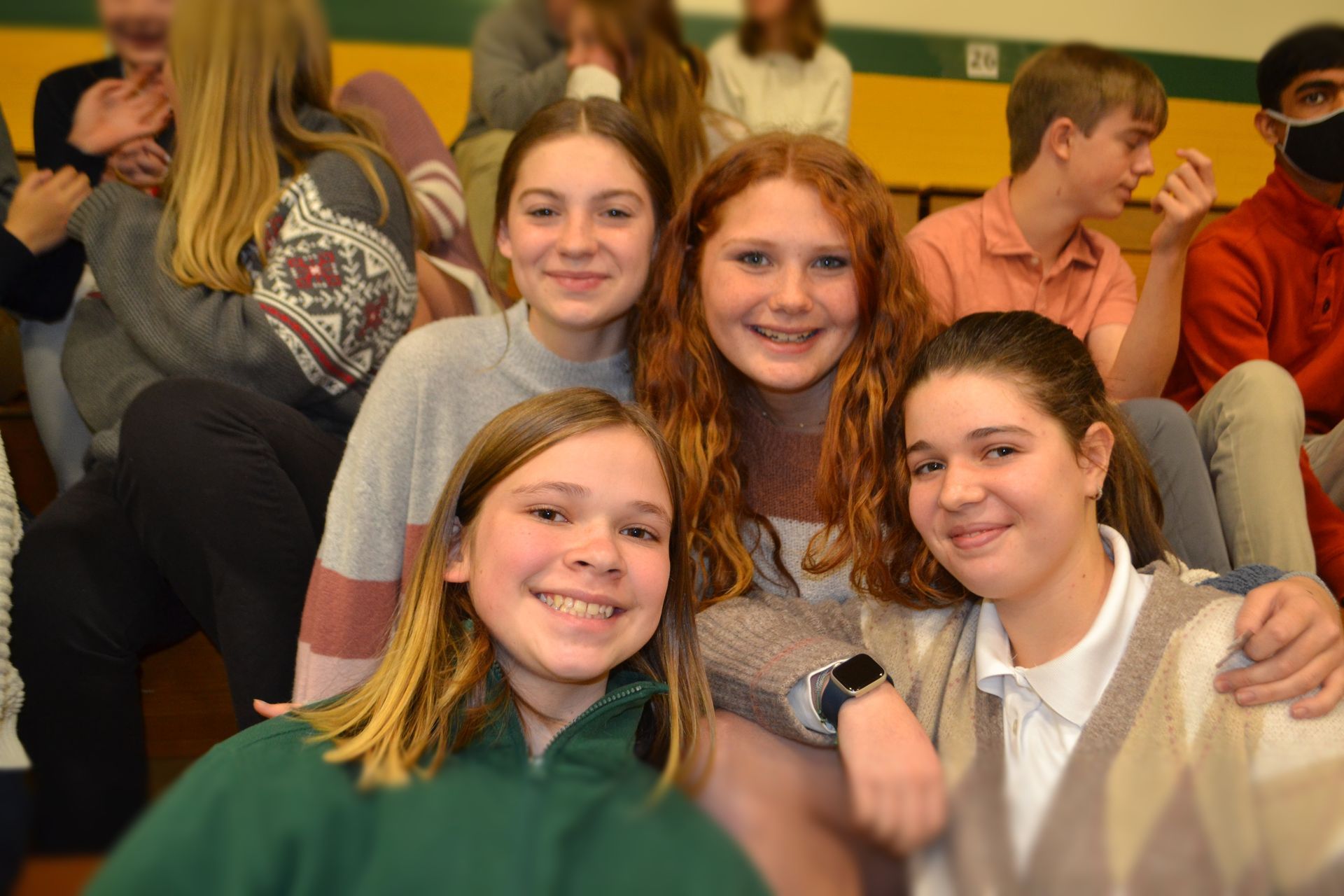 group of students smiling bleachers in gym