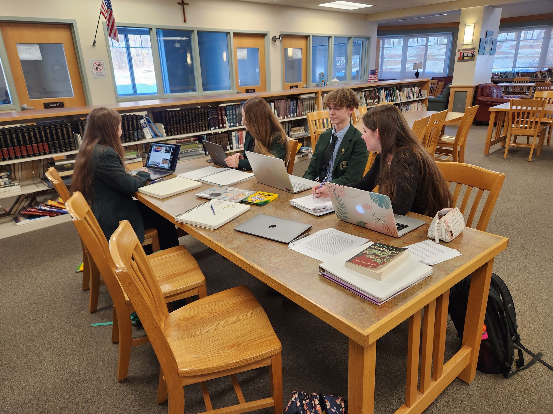 group of students at a table on laptops and reading in the library