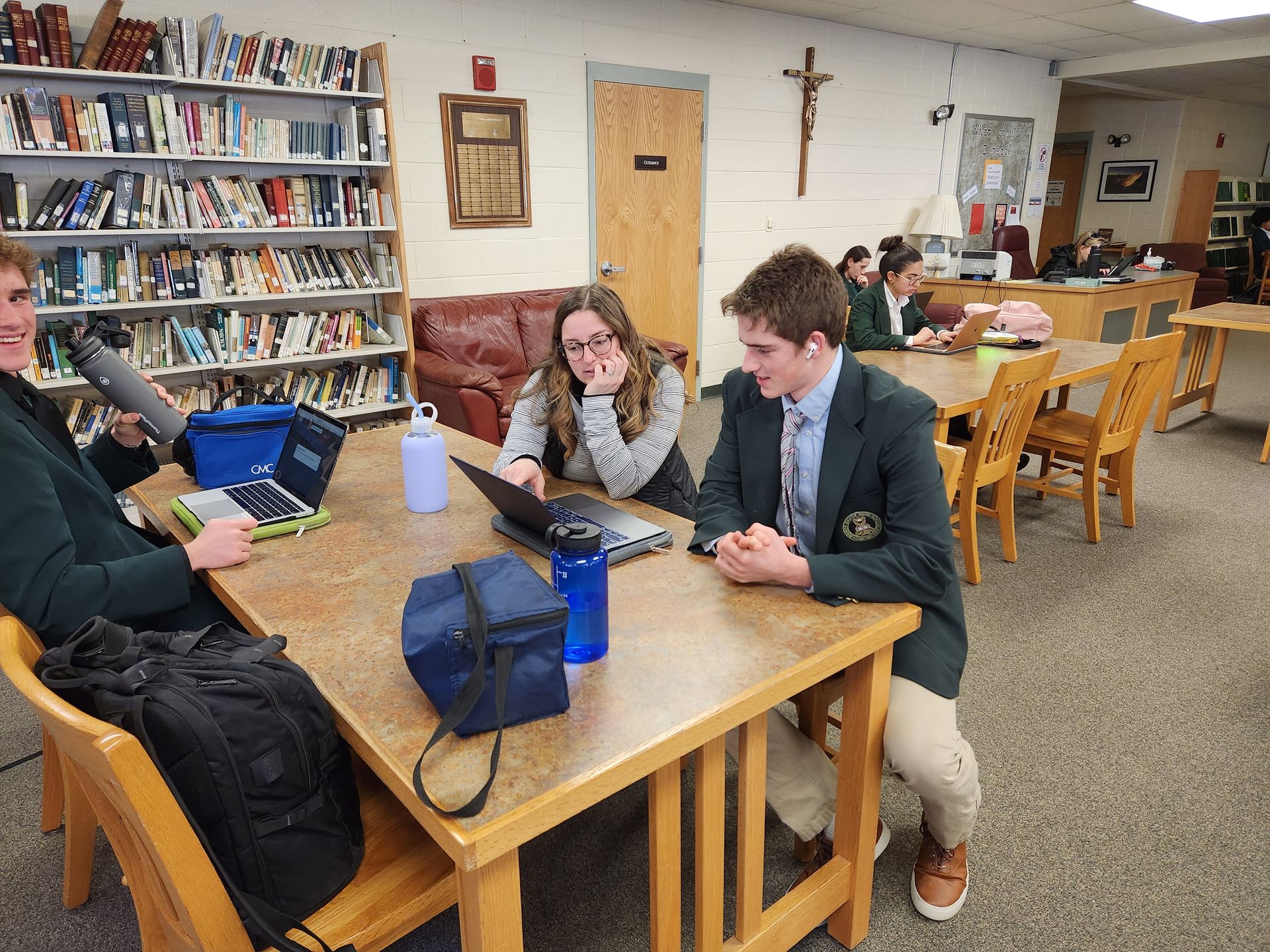 student at desk with computer, book shelf in library