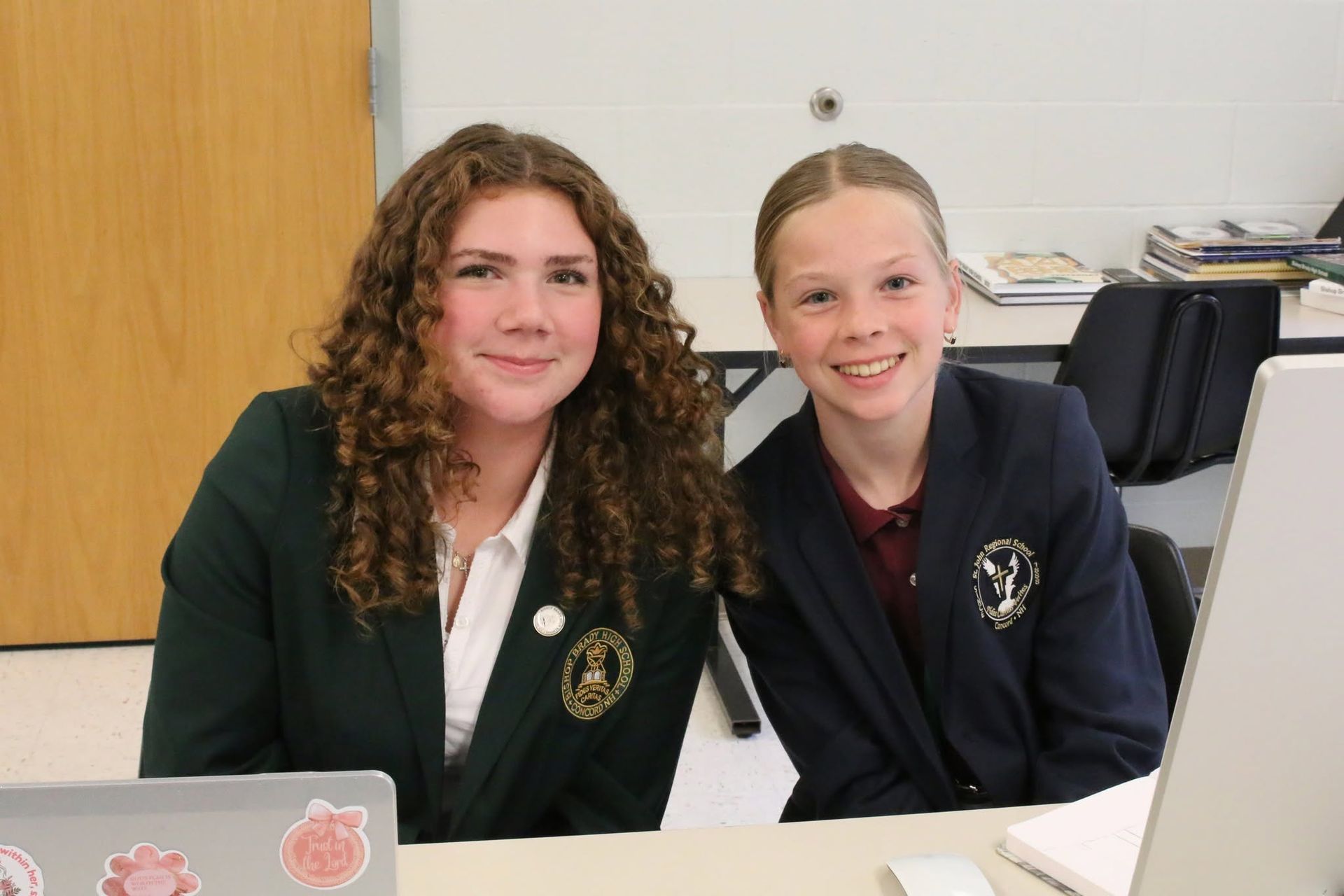 2 students in uniform sitting in class, computers
