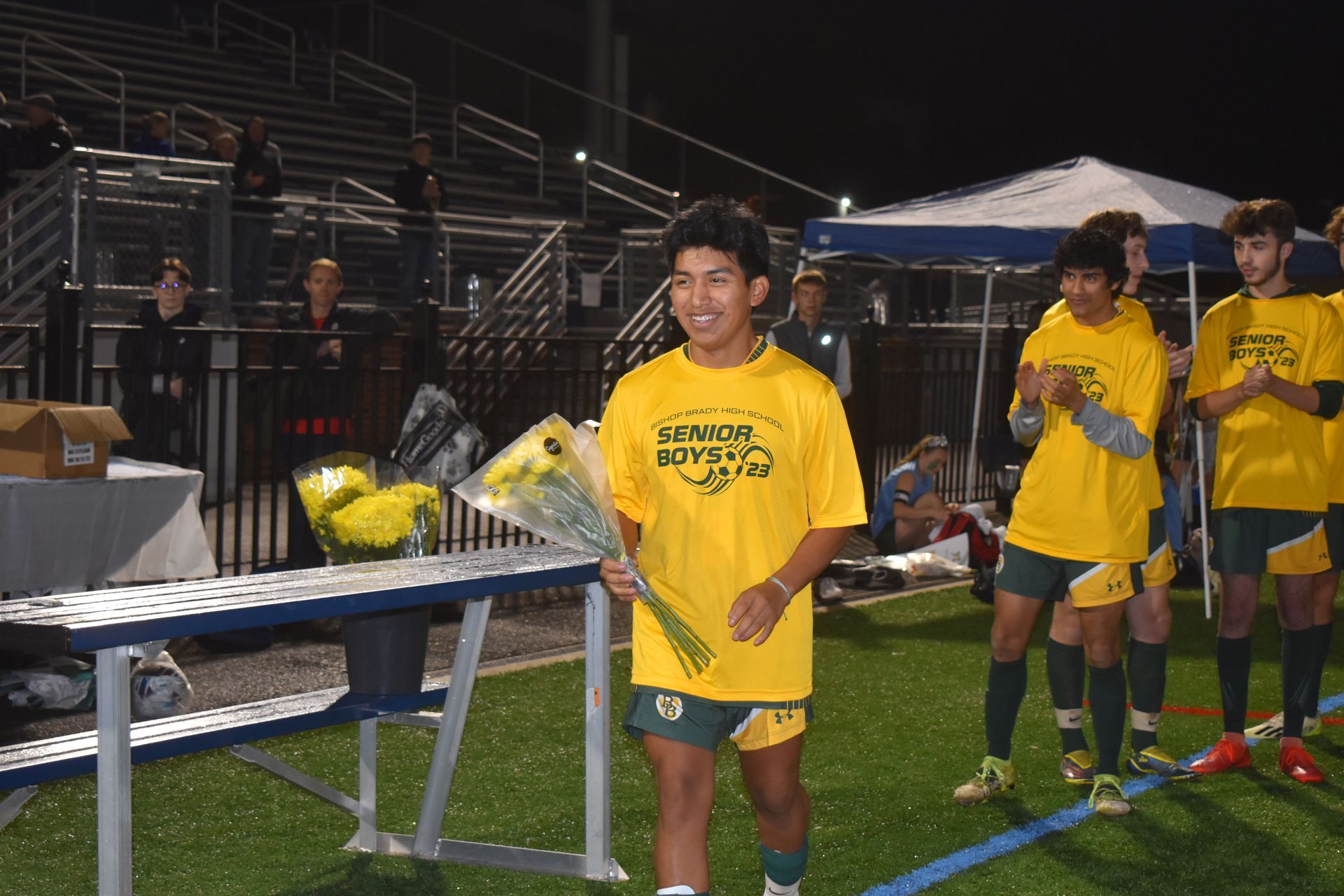 Male wearing yellow shirt on a field with yellow flowers in his hand