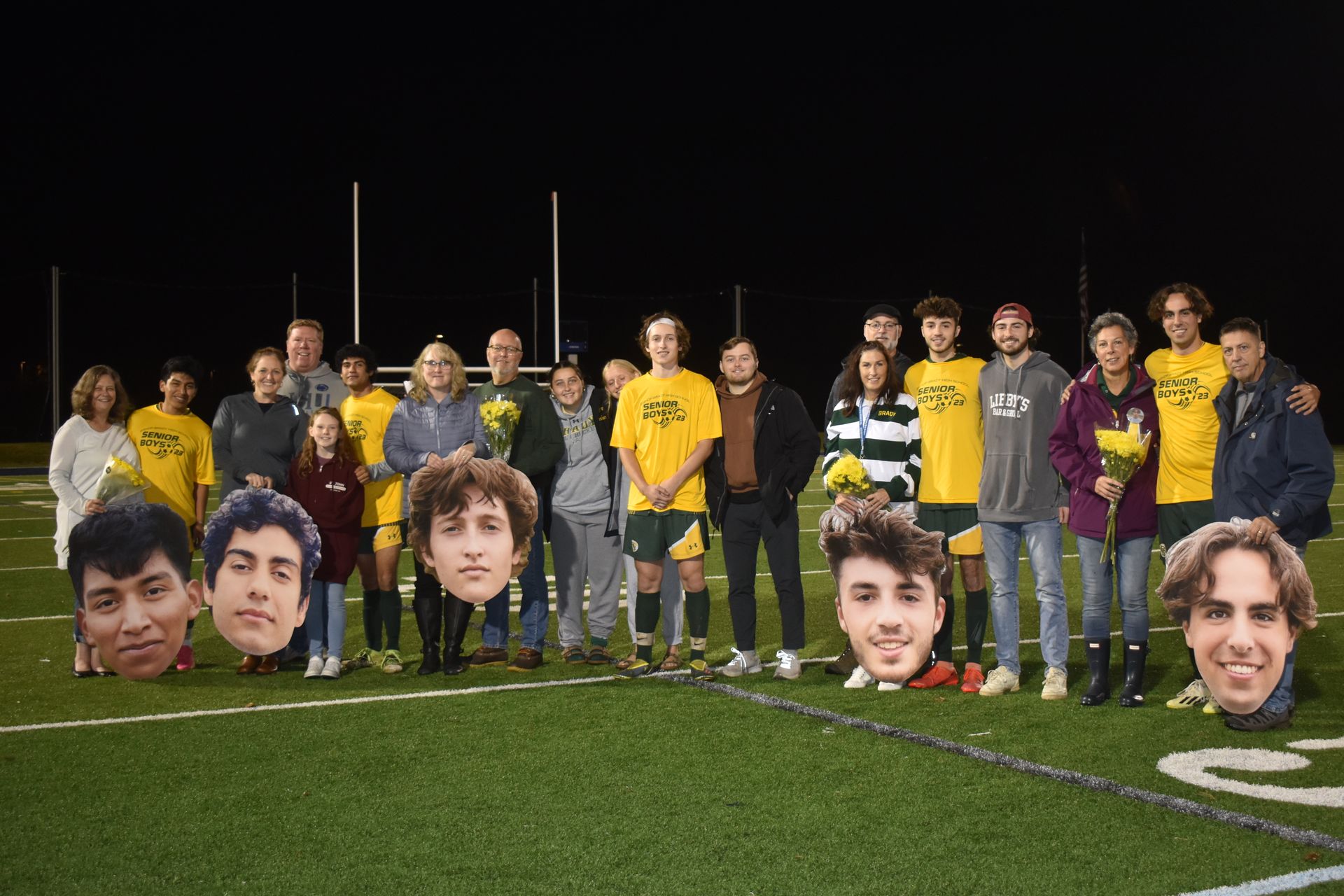 Group of male senior soccer players with their parents outside with goal post in the background