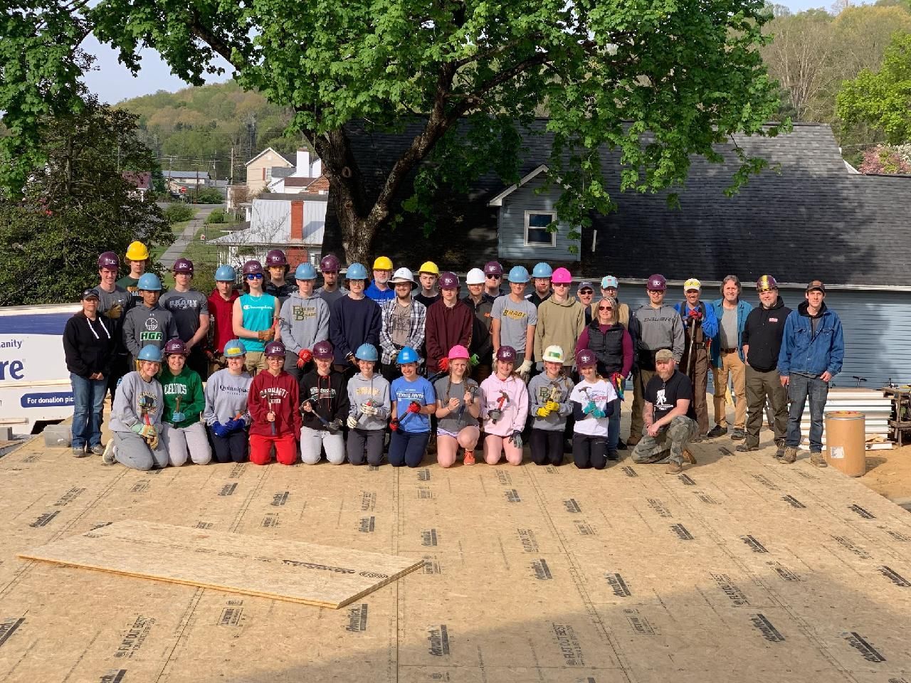 A large group of 25 students at a Habitat for Humanity construction site. 