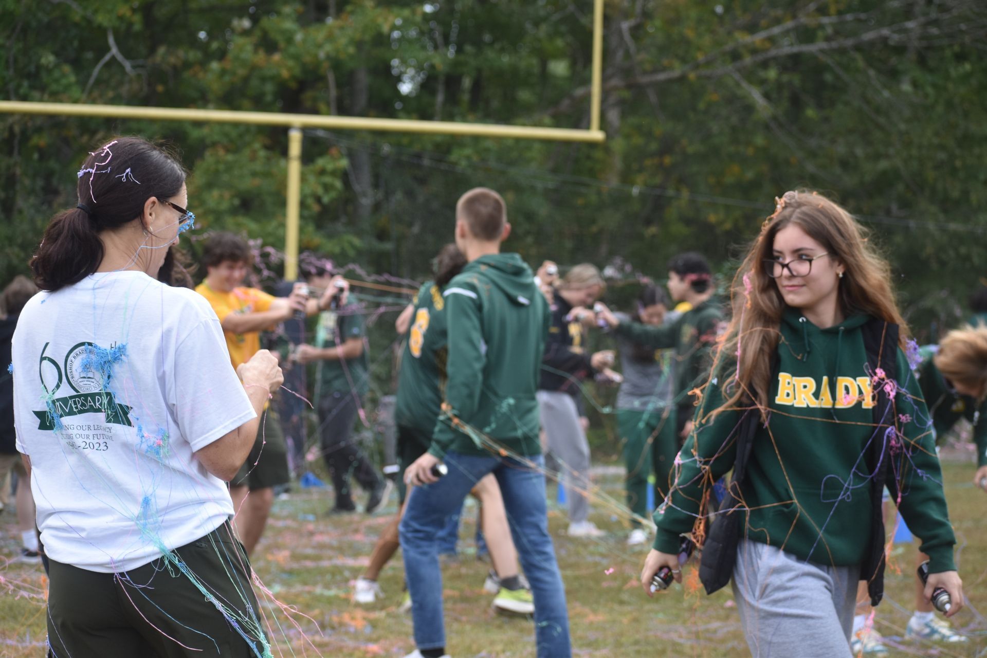 group of students walking with silly string everywere and a football goal in the background they are outside