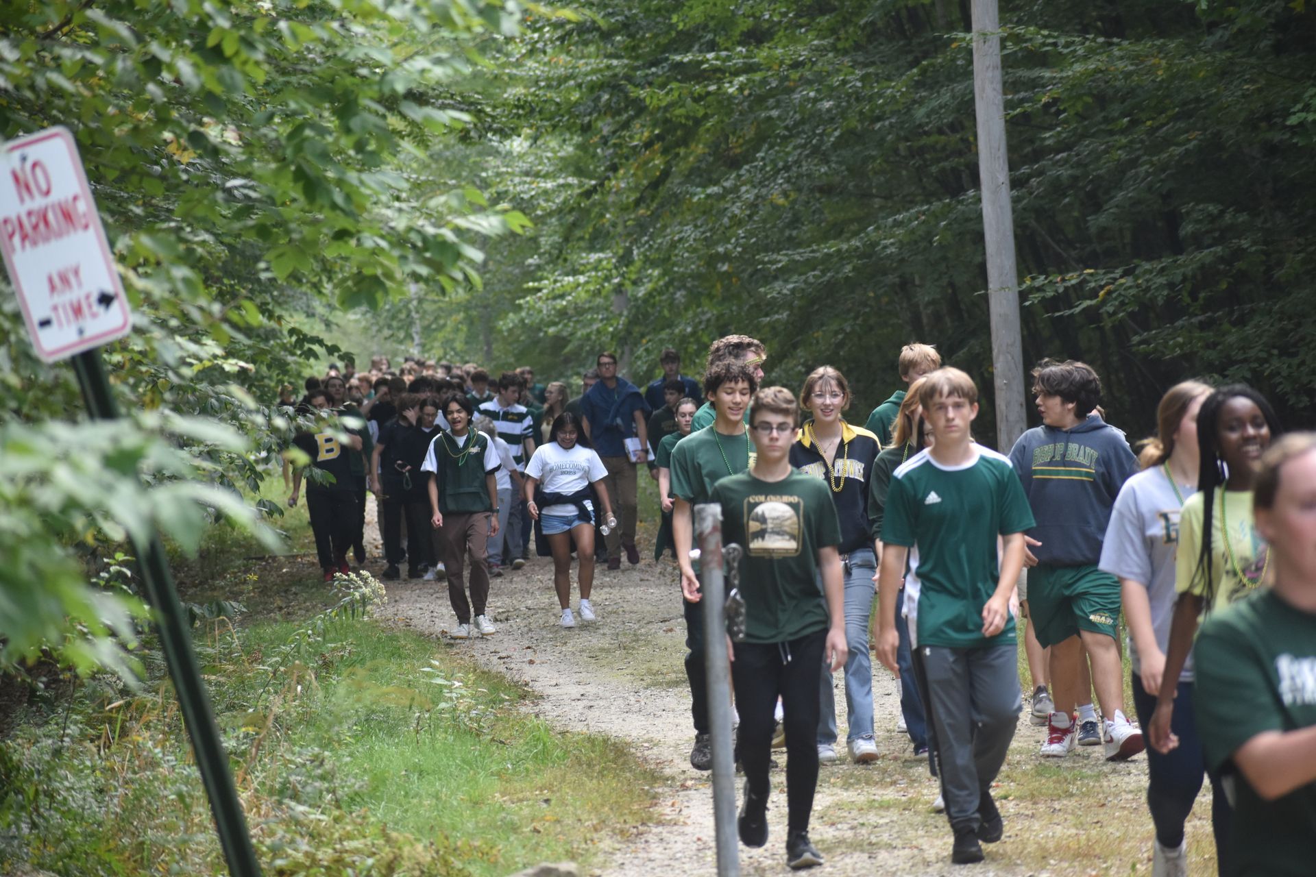 group of students walking outside on dirt path with trees