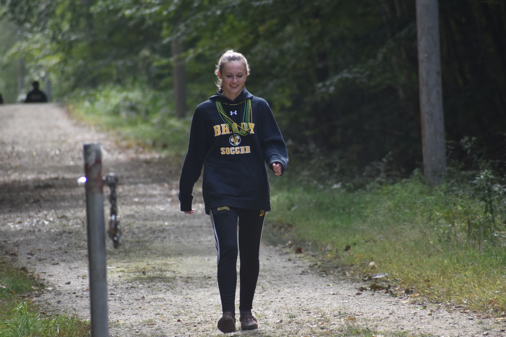 student walking on dirt path with trees