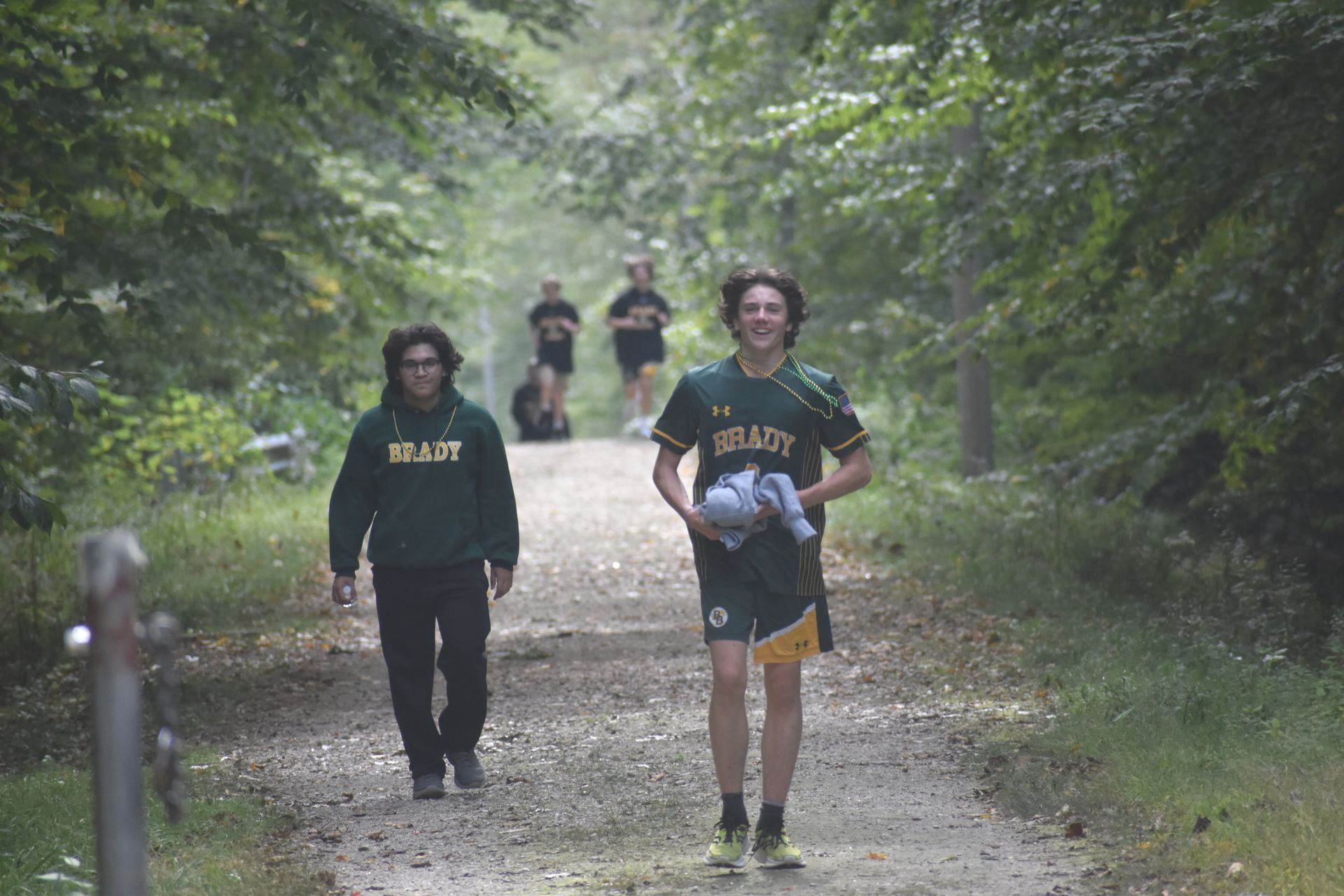 students walking on dirt path with trees