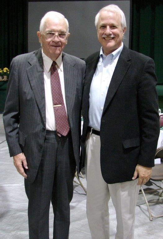 2 men in suit jackets smiling in a room