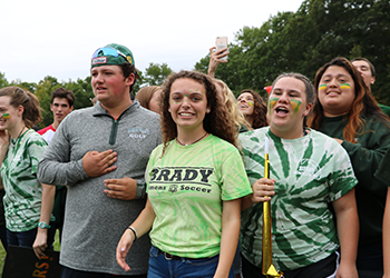 group of male and female students outside smiling with green clothing