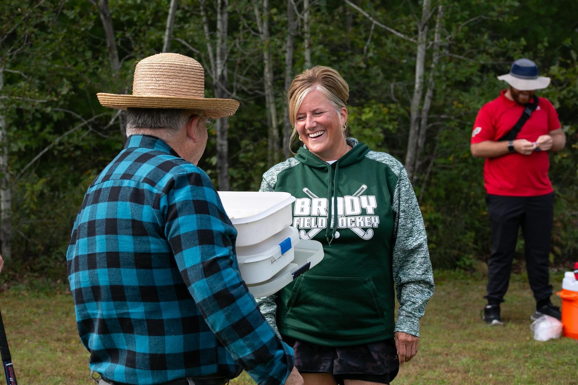 Female smiling with male carrying items on a sports field. 