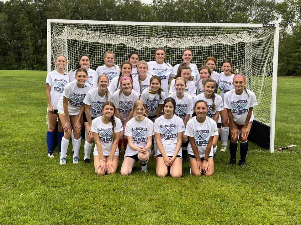 field hockey female team portrait outside in front of net. 