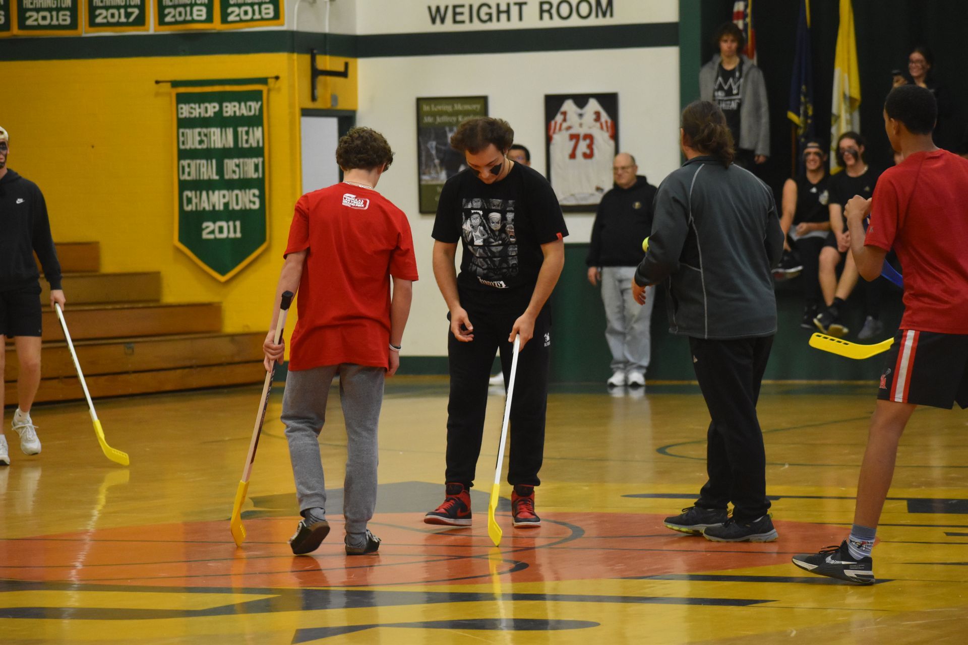 4 students playing floor hockey in the gym