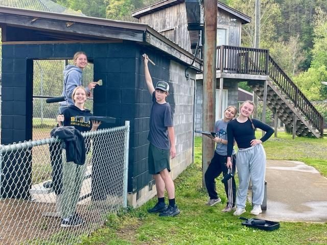students painting outside, baseball dugout