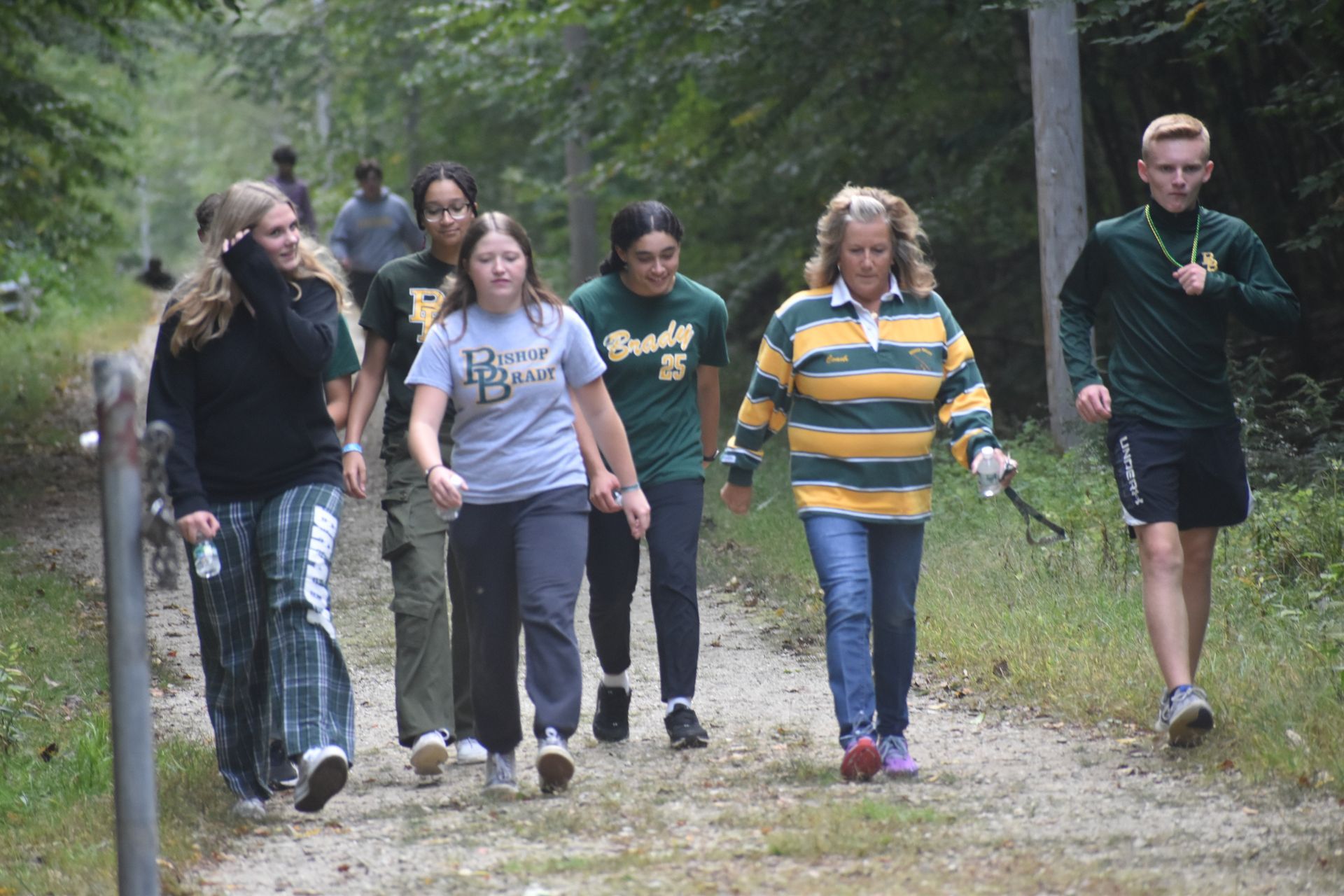 students walking on dirt path with trees
