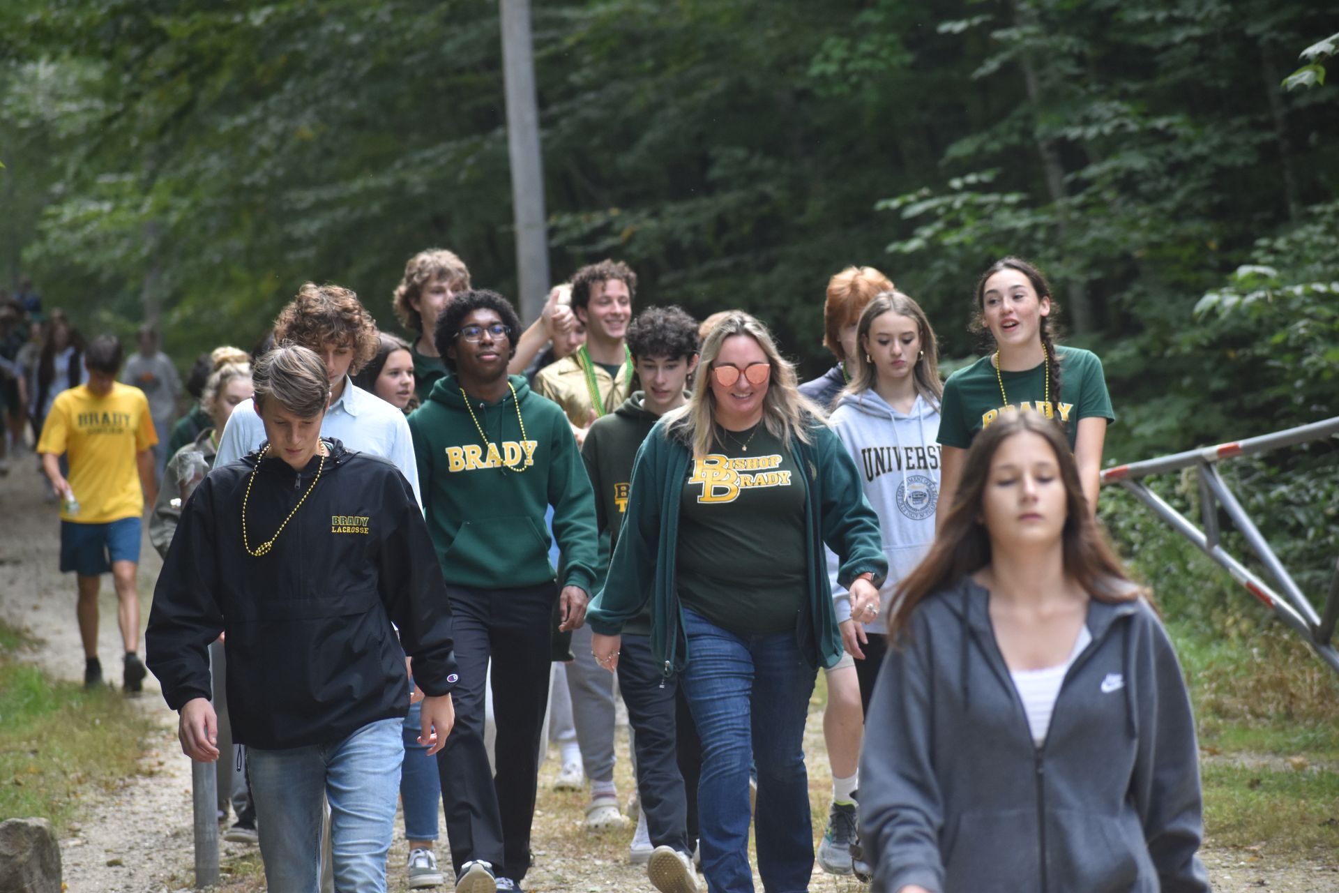 a group of students walking outside, trees behind them they are smiling