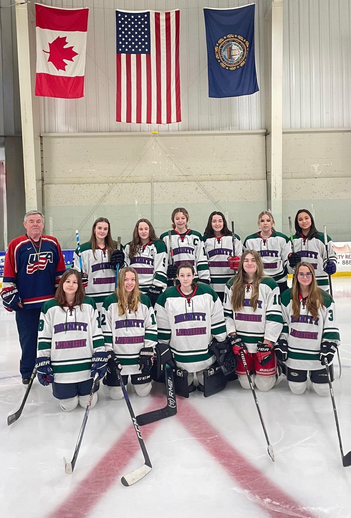 image of a hockey team and 3 flags hanging in ice arena  