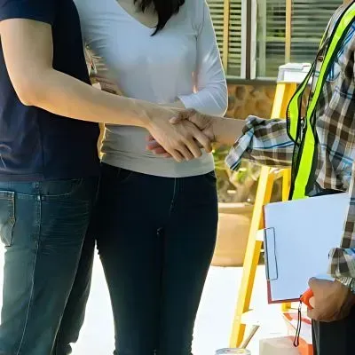 A happy couple shaking hands with a driveway contractor in Dunedin.