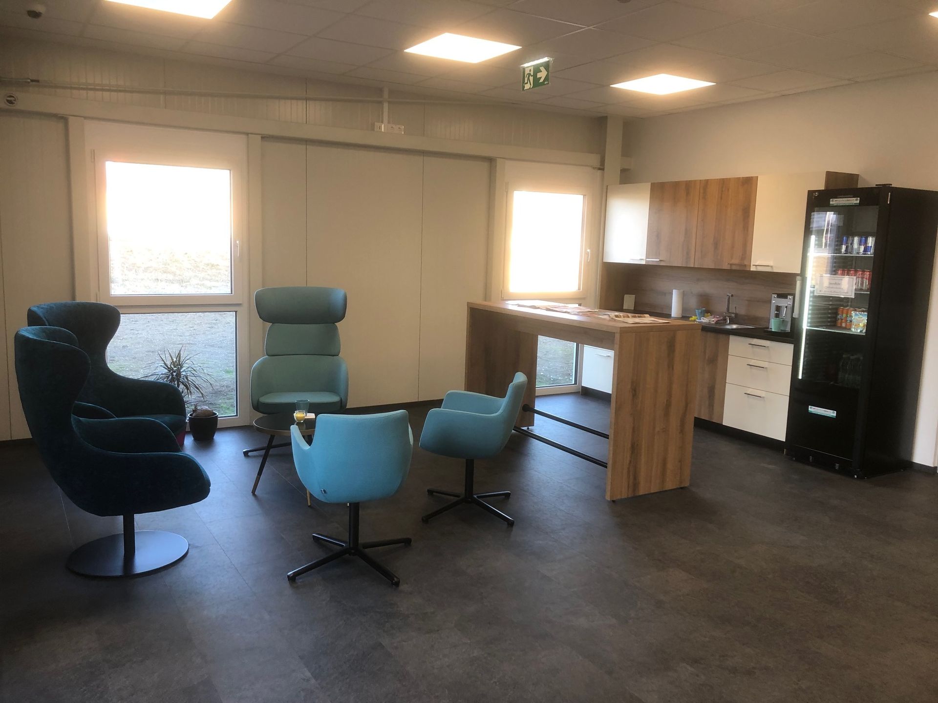 Moderne Bürolounge mit blauen Stühlen, einer Holzbar und einem Verkaufsautomaten