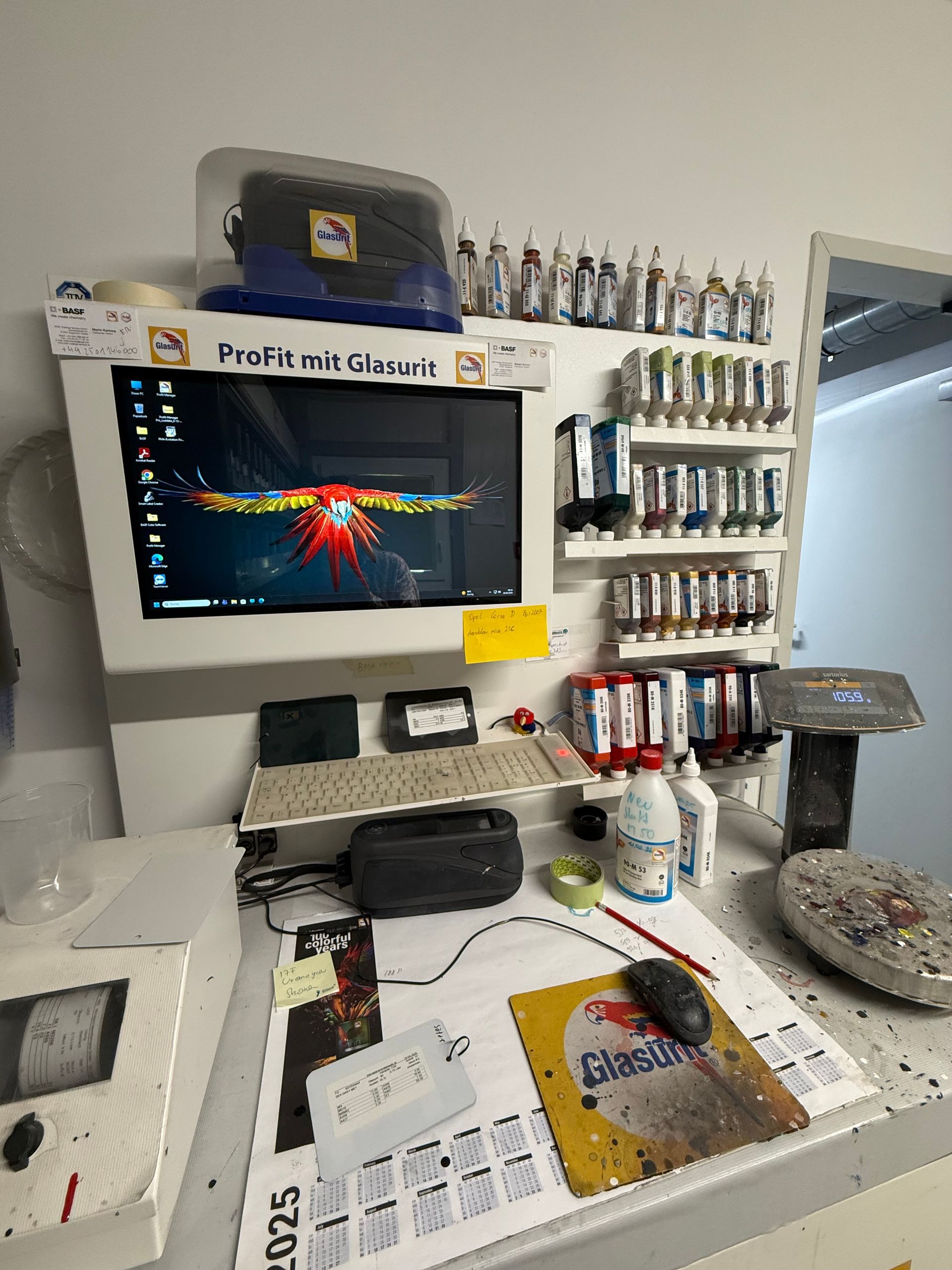 Unordentliche Theke mit Computermonitor, Regalen voller Flaschen und Büromaterialien in einem Einzelhandelsgeschäft.