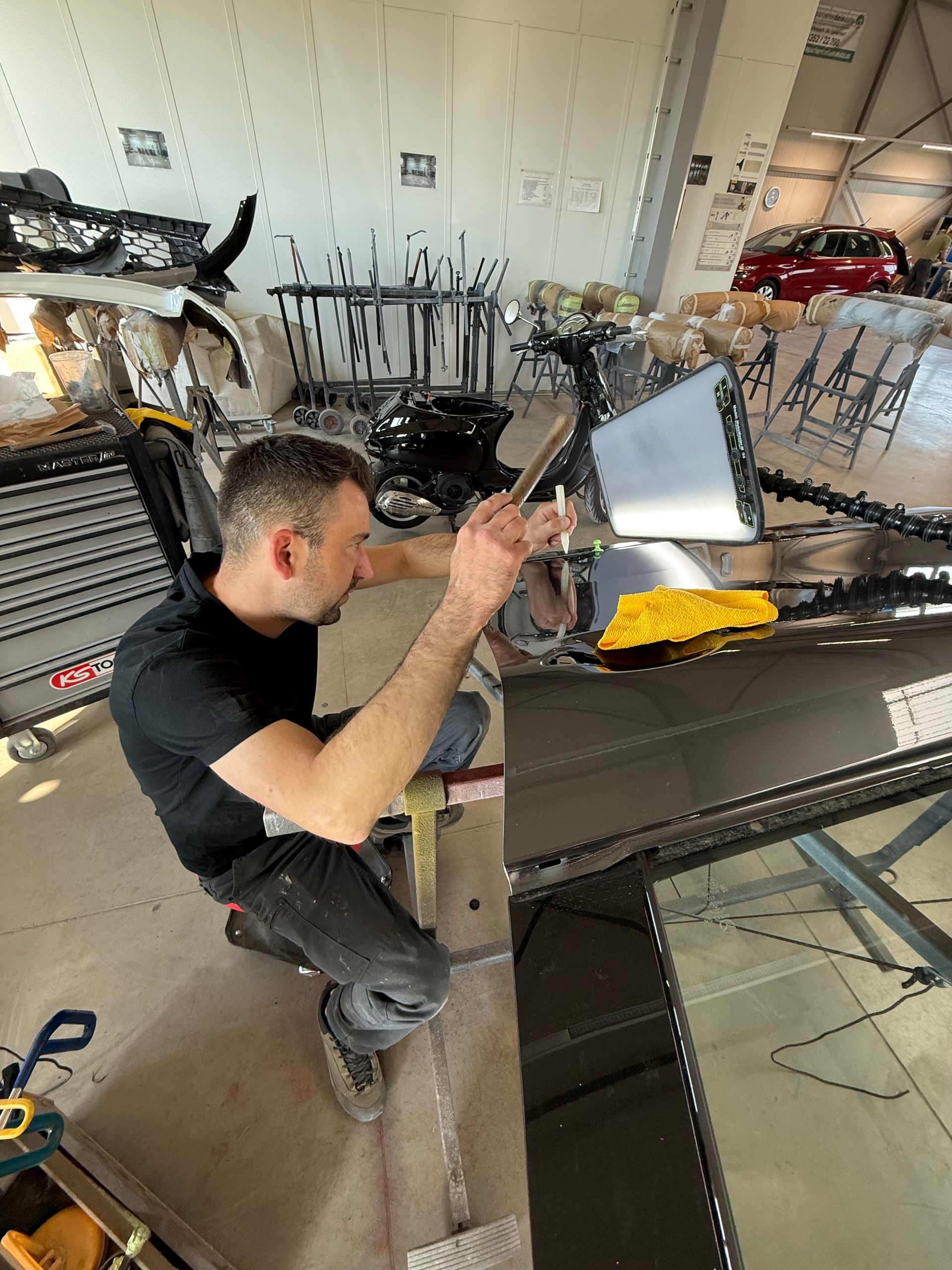 Eine Person arbeitet in einer Werkstatt an einem Metallrahmen und benutzt dabei ein Werkzeug
