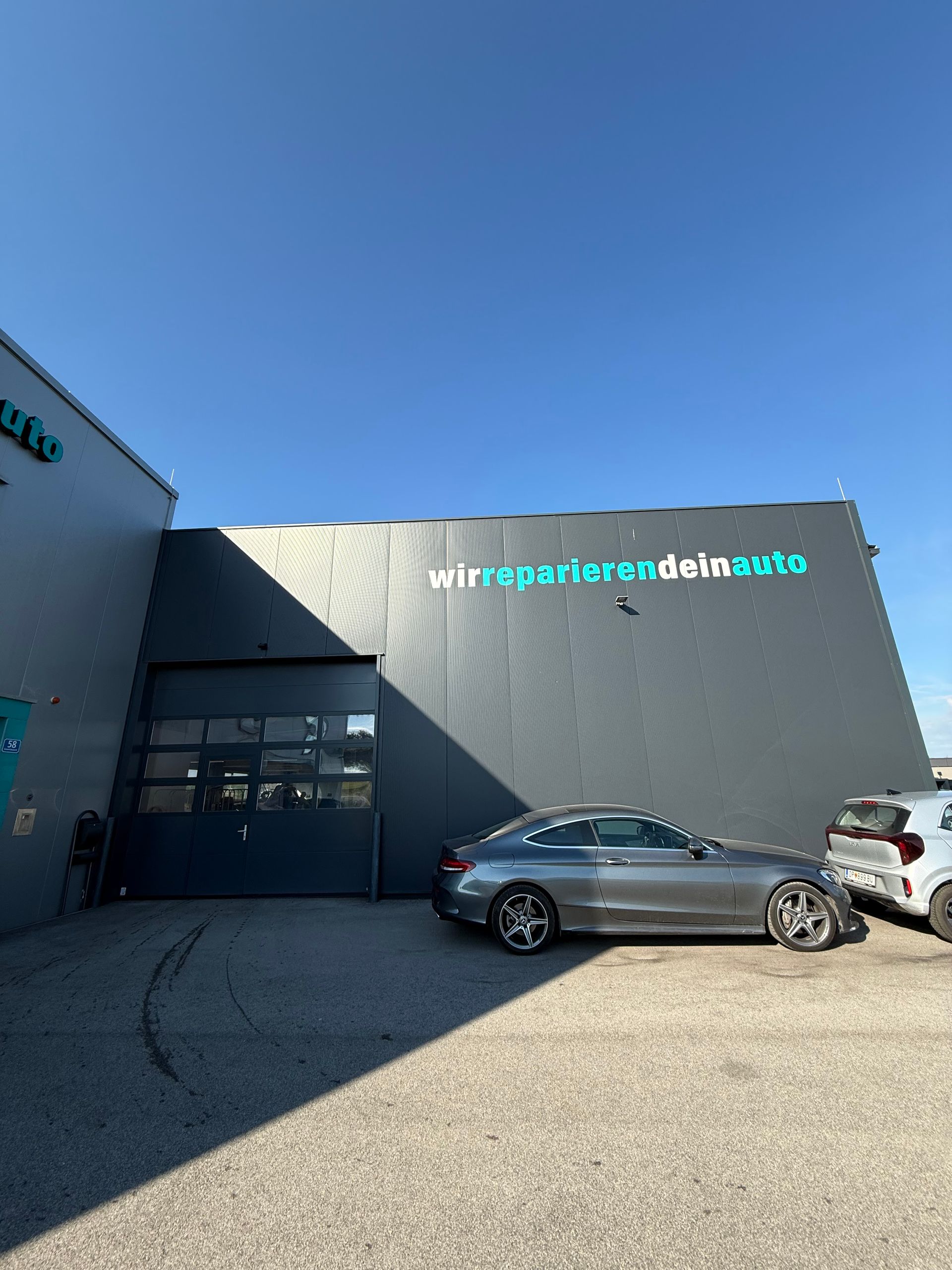 Moderne Gebäudefassade mit geparkten Autos unter klarem, blauem Himmel