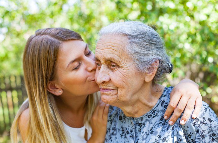 A daughter kissing her grandmother on the cheek
