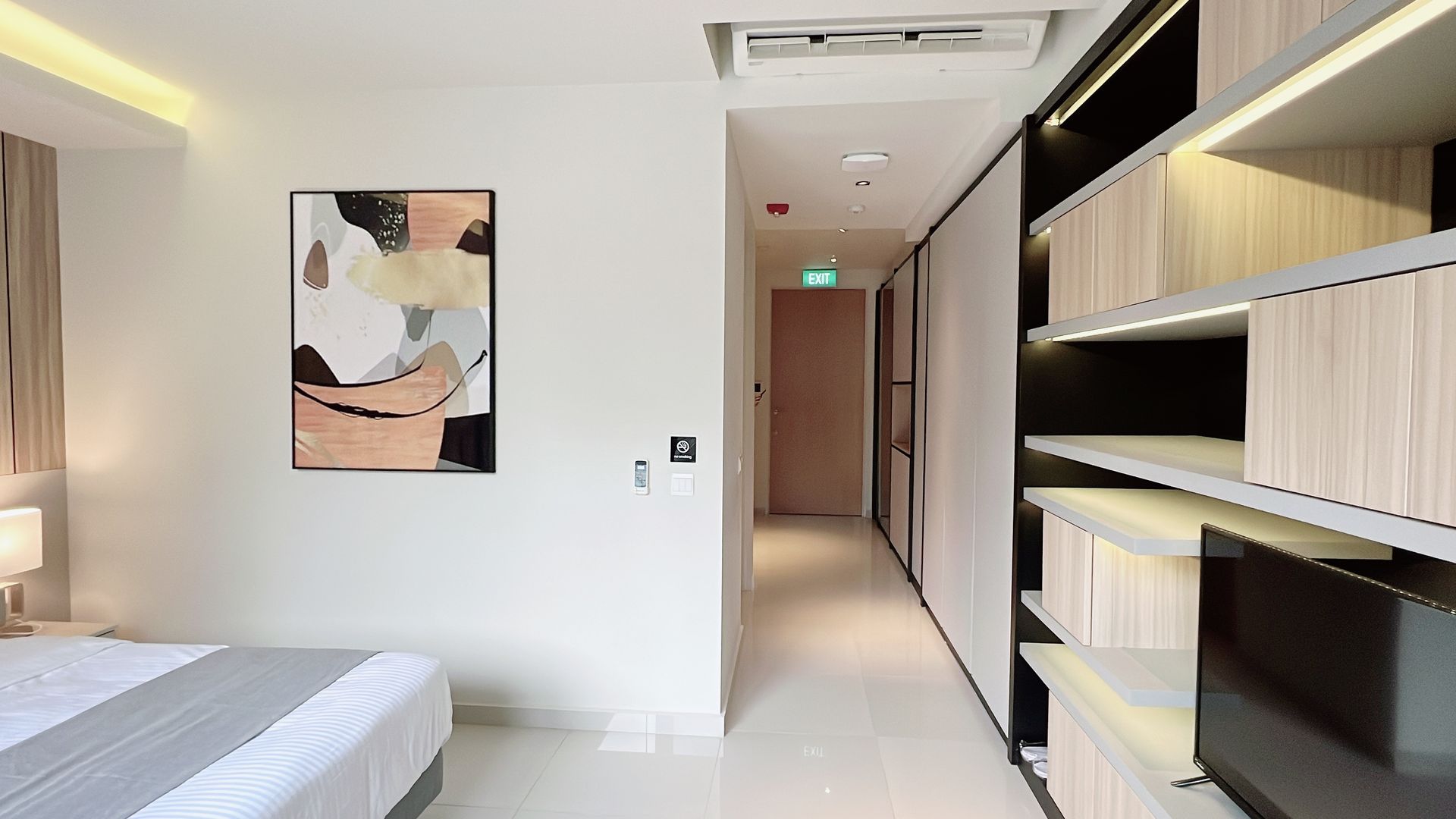 Modern bedroom with bed, abstract wall art, hallway, and built-in shelves along the right wall