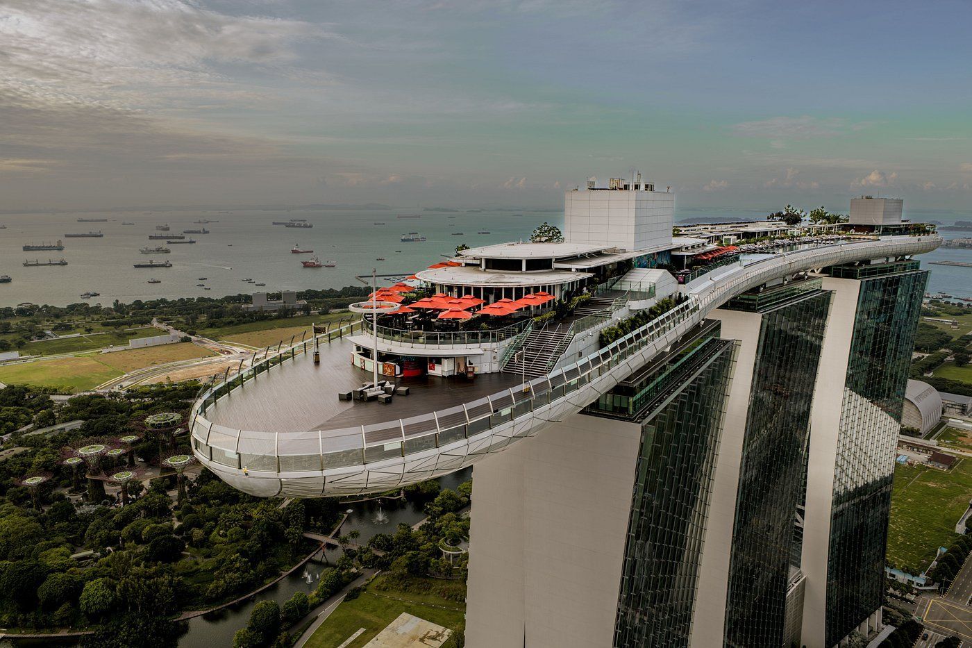 Curved rooftop observation deck atop tall towers, with city skyline and water in the background