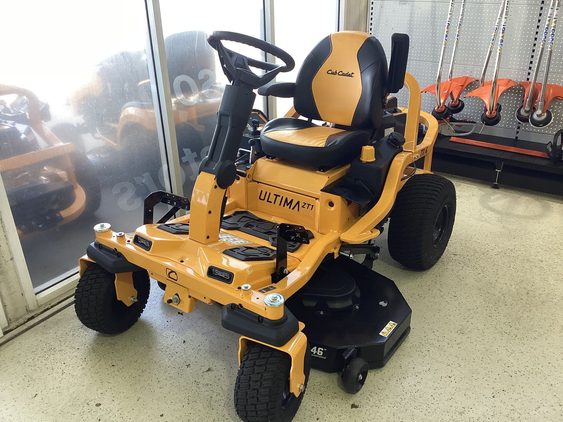 A Man Is Sitting On The Grass Fixing A Lawn Mower — Coastal Farm & Motorcycles In Innisfail, QLD