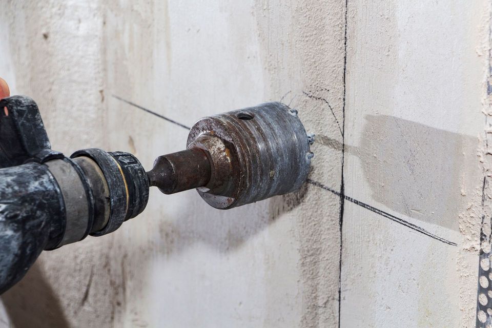 Una persona está usando un martillo para perforar un agujero en una pared.