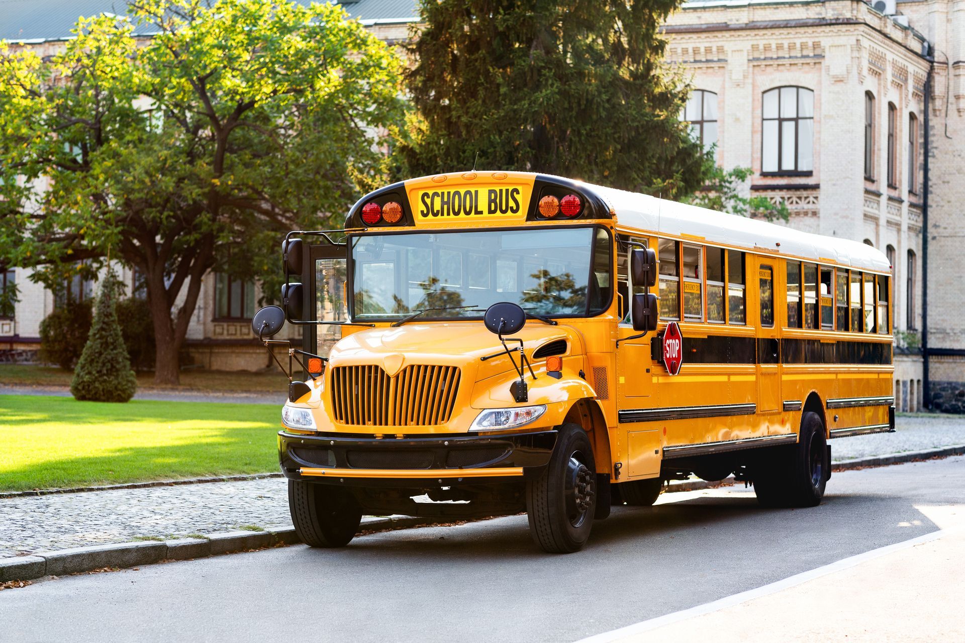Yellow school bus parked in front of a brick building.