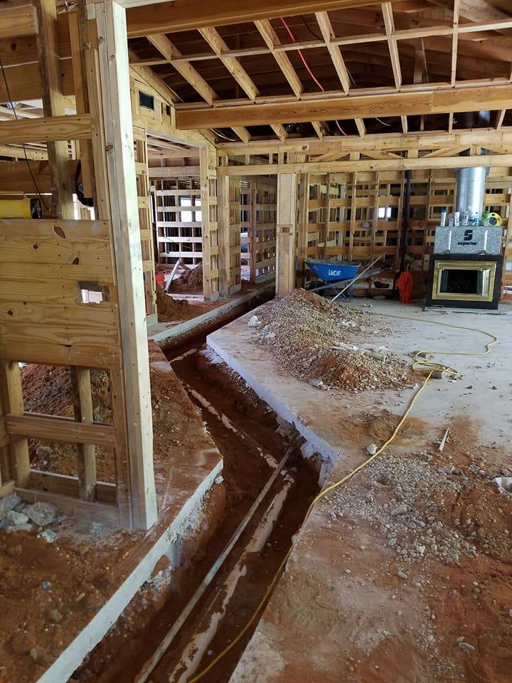 Interior of a house under construction with exposed framing, debris, and a saw on the floor.