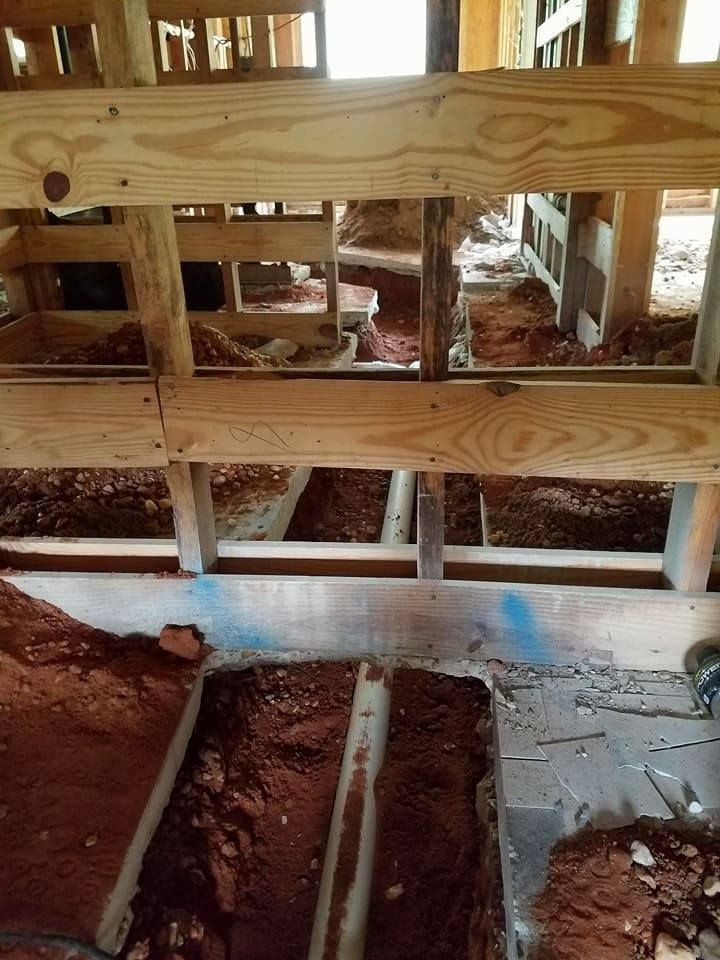 Exposed floor joists and subfloor framing over a dirt crawlspace in a house under construction
