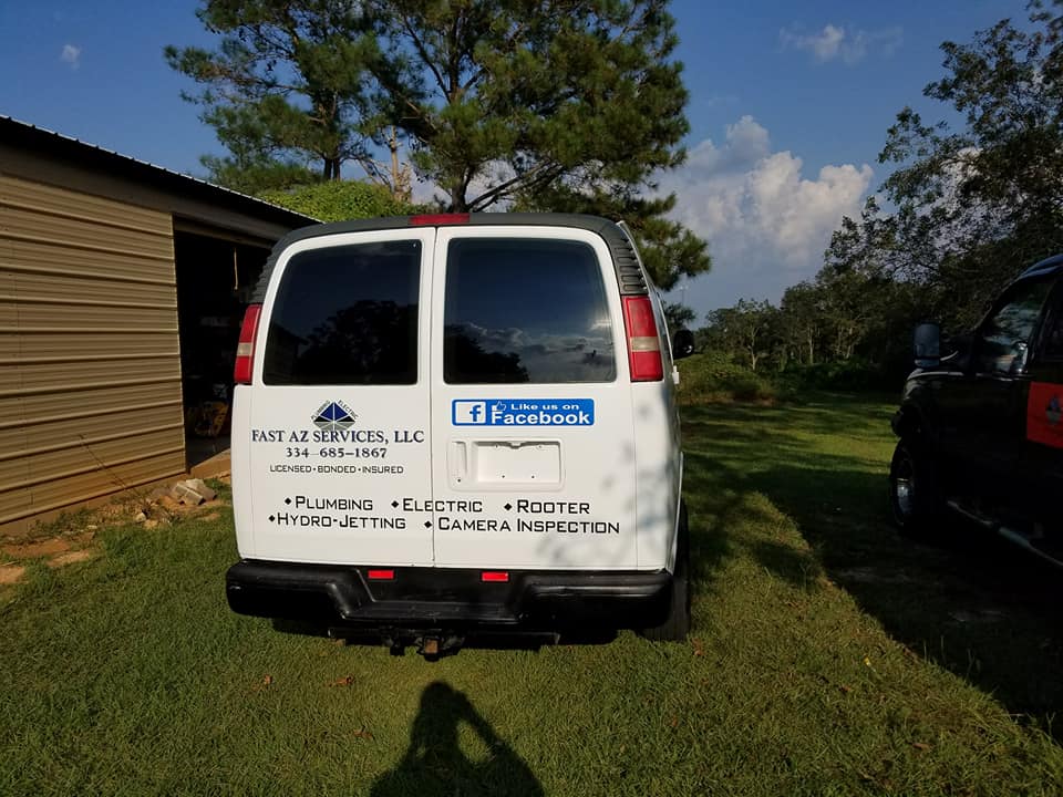 White service van with company logos parked on grass beside a building under a blue sky