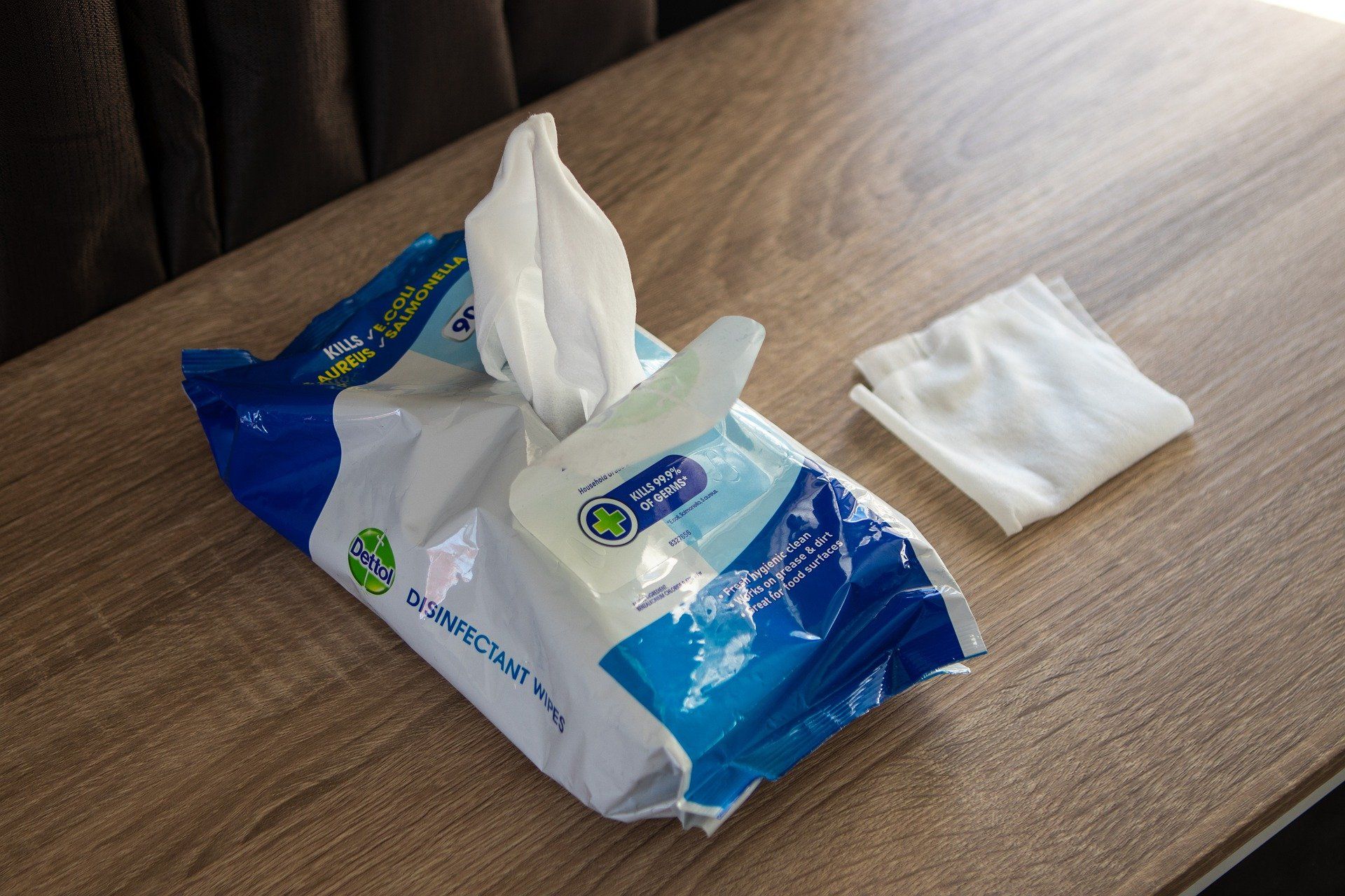 Blue-and-white tissue box with tissues on a wooden table, with a folded napkin nearby