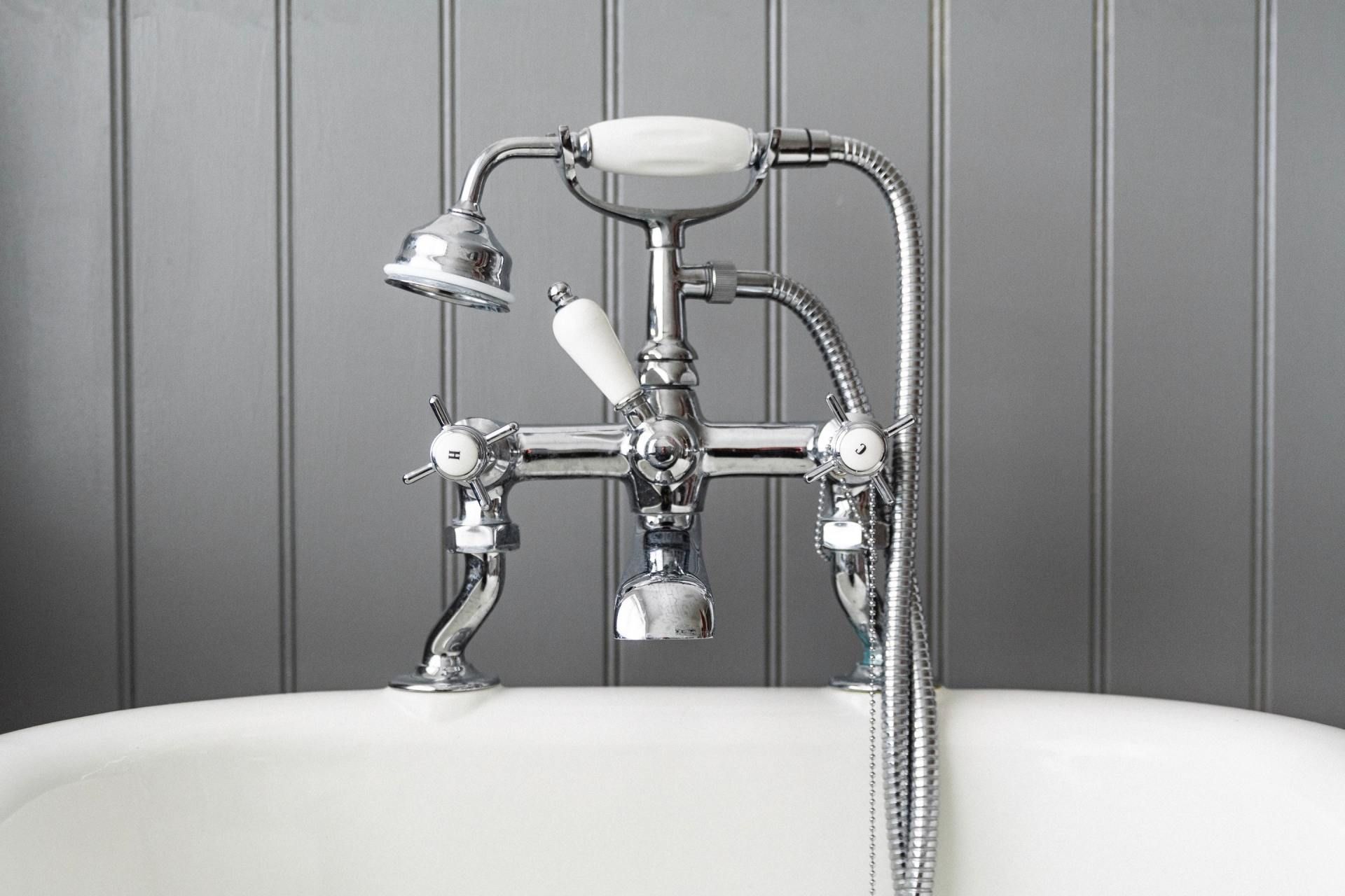 Chrome vintage-style bathtub faucet against a gray tiled wall