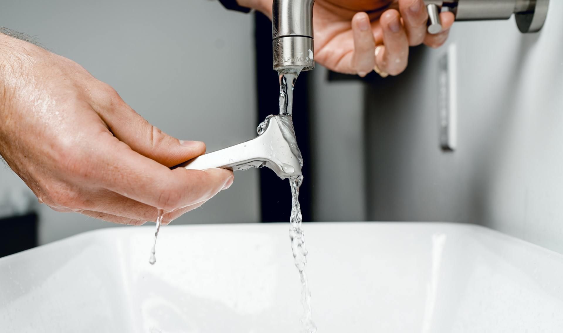 Hands rinsing a white razor under a running faucet over a sink