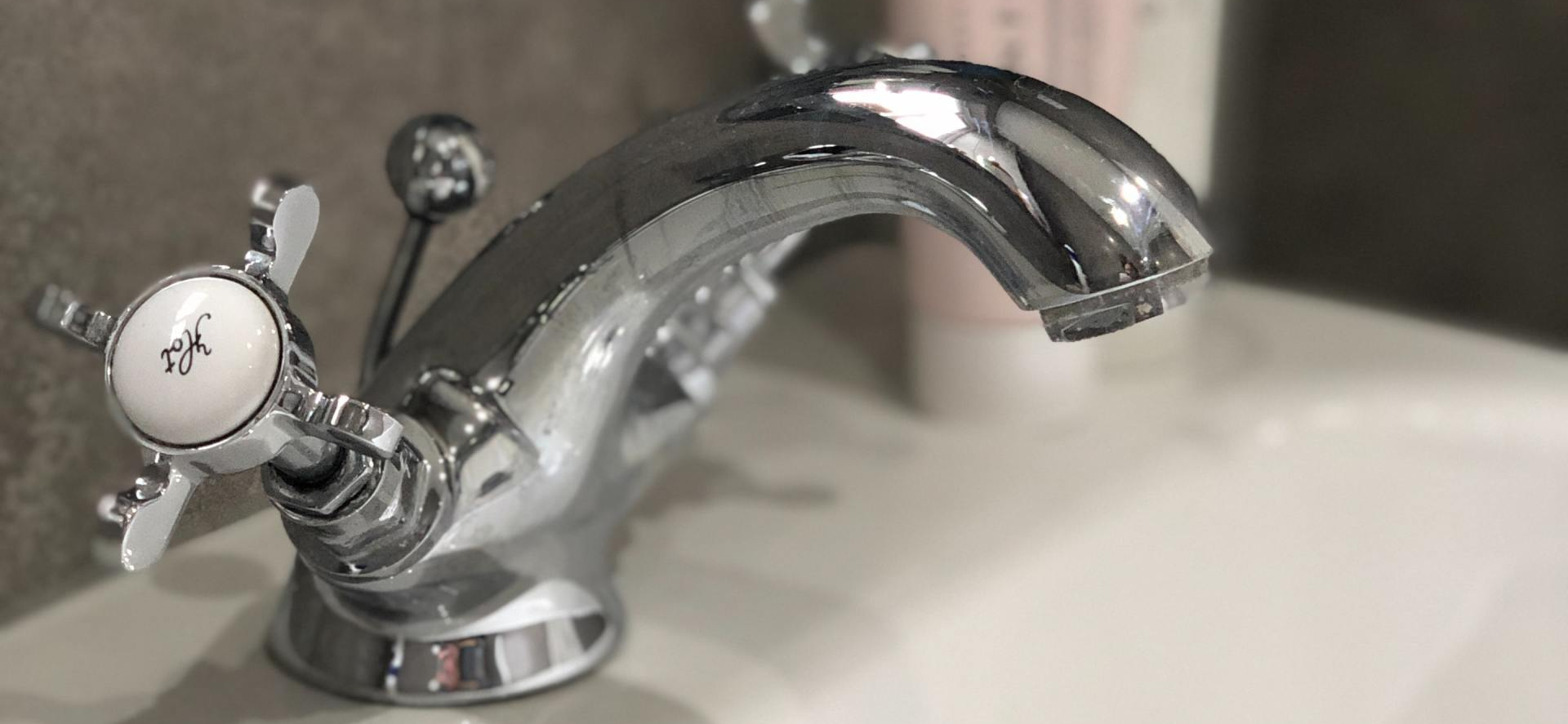 Chrome bathroom sink faucet with two handles on a white countertop